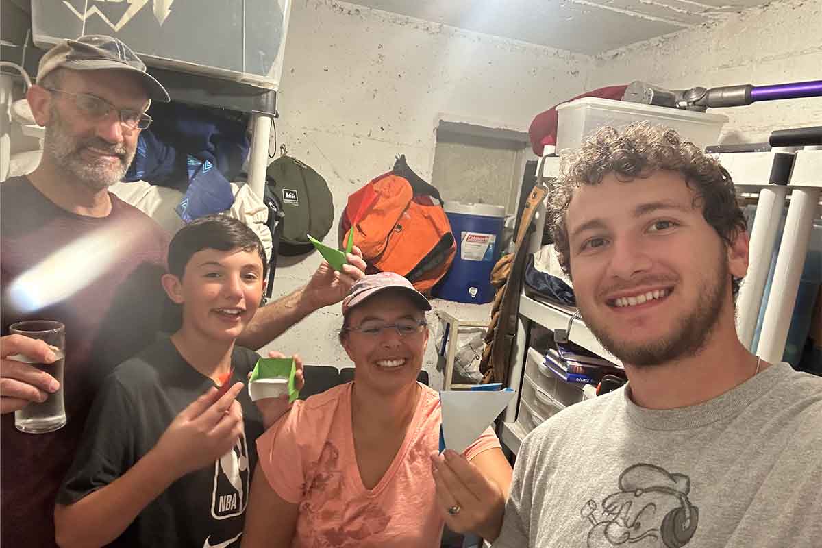 Picture of me (right), Adam and Abigail and their youngest son Yisrael in their shelter during an attack today. Sometimes we do origami in there to pass the time that is what they are holding up.